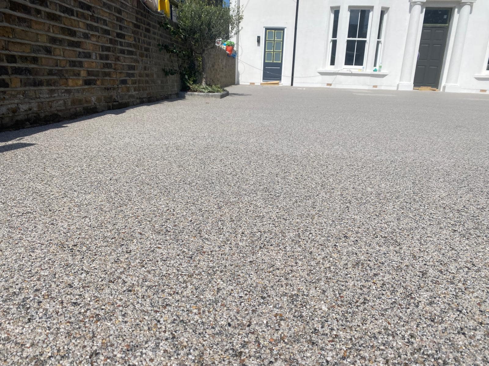 Curte cu pietriș în fața unei case albe.