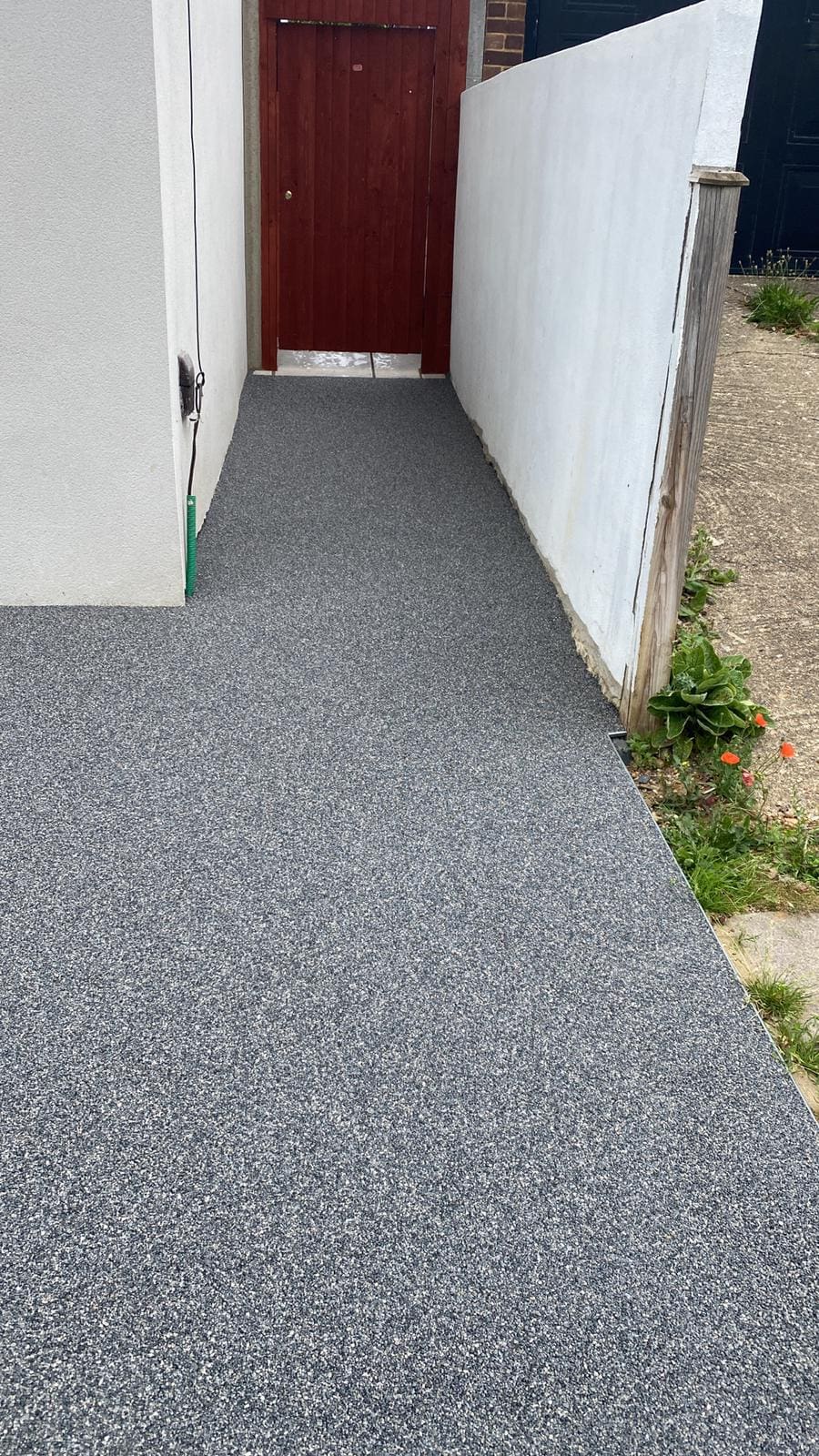 Alee pavată cu gard și ușă de lemn roșu.